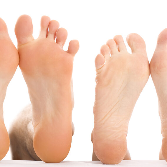 Two pairs of bare feet with soles facing forward